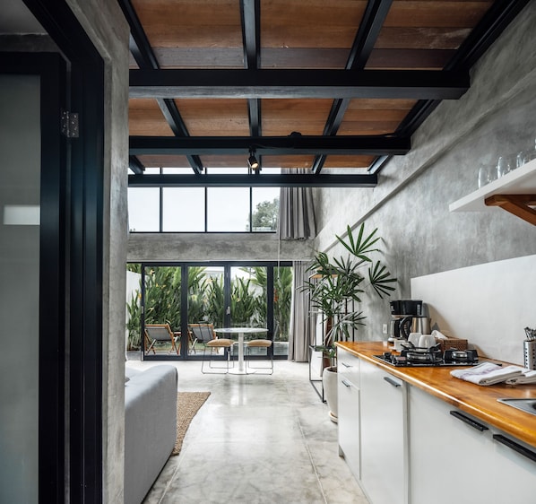 Una cocina moderna con encimera de madera, una cafetera y un comedor con mesa y sillas.