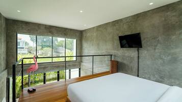 Un dormitorio moderno con una cama grande, un televisor montado en la pared y un balcón con barandilla.