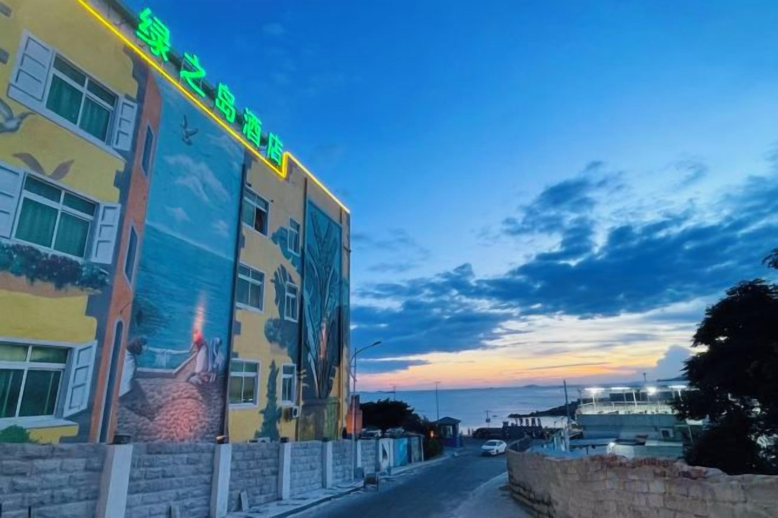 Un edificio con un gran mural en la fachada, un letrero que indica un hotel y un cielo despejado.
