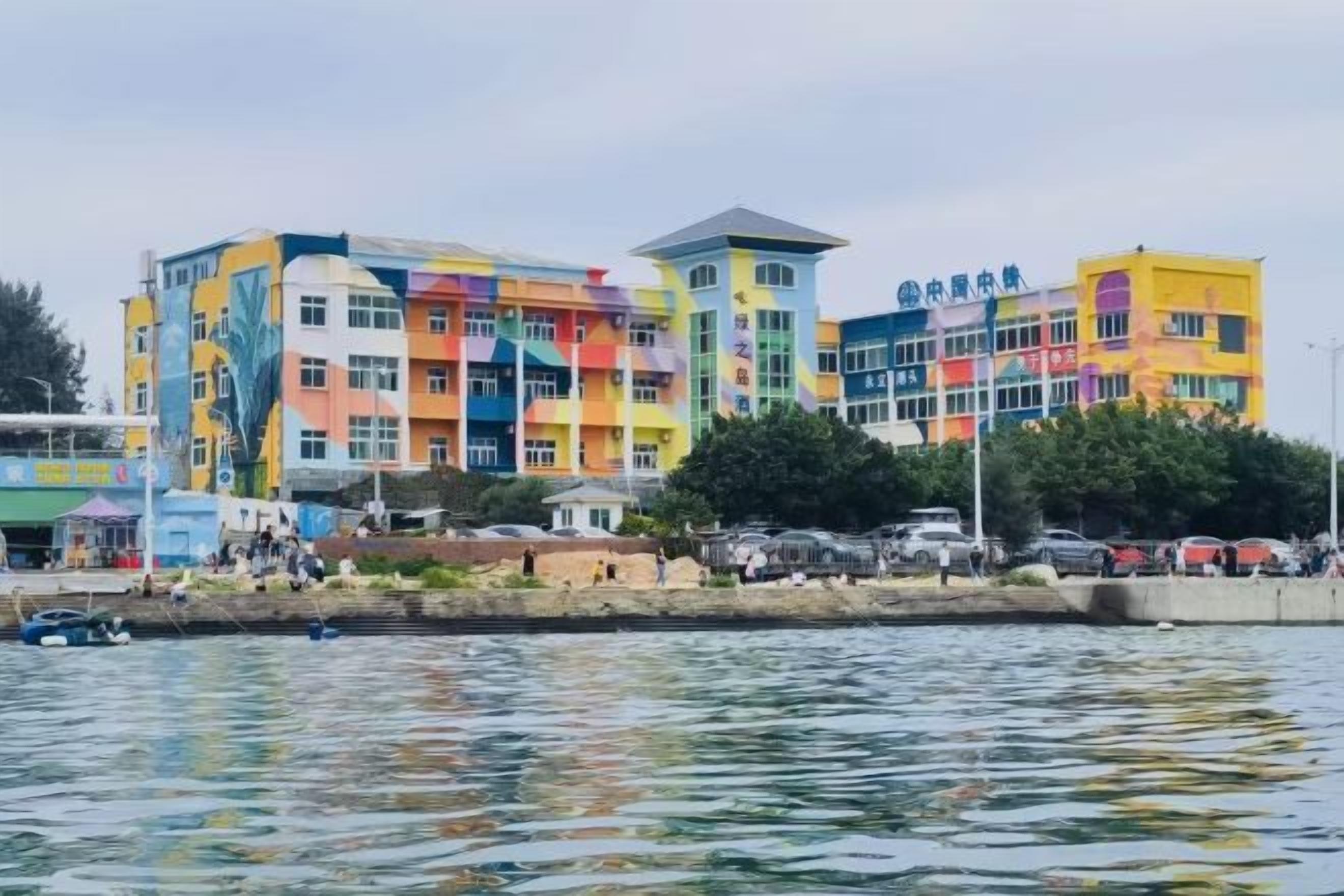 A multi-story building with a colorful facade, situated by a body of water.