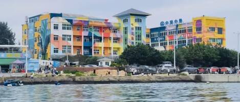Un edificio de varios pisos con fachada colorida, ubicado junto a una masa de agua.