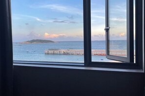 Vista a través de una ventana que muestra cielo despejado, una masa de agua y una isla distante.
