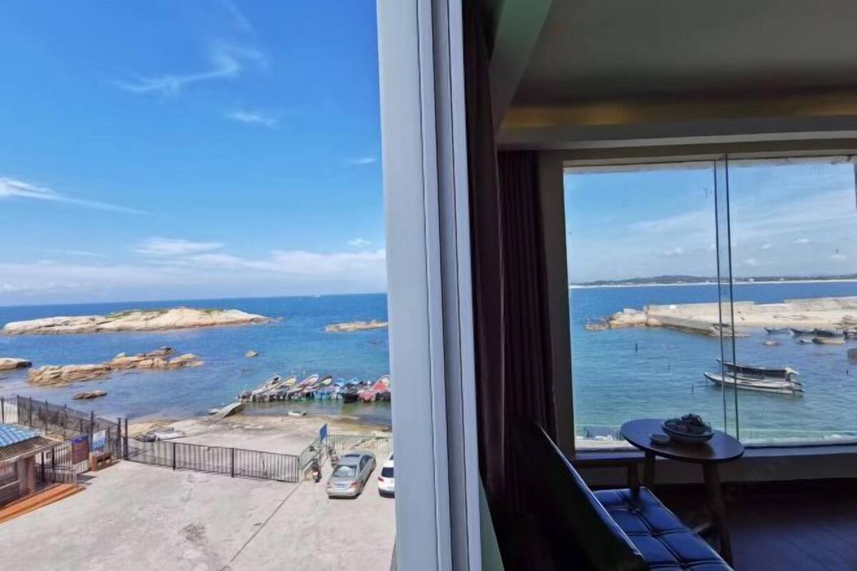 Een balkon met uitzicht op zee, een tafeltje en een bankje.