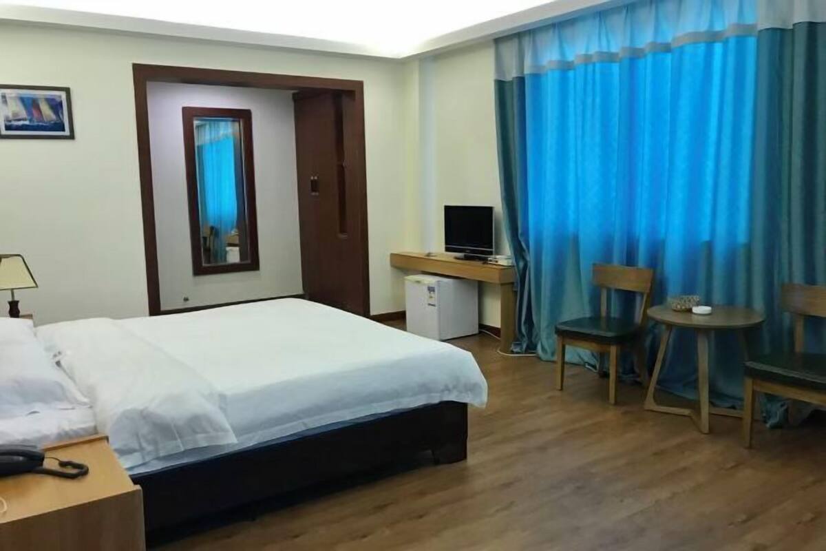 Een hotelkamer met een bed, een bureau met een computer, een stoel, een klein tafeltje en een televisie.