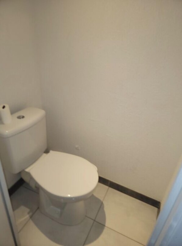 Bathroom features a toilet and tiled floor.