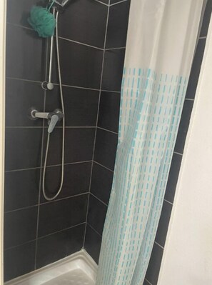 Shower area features a showerhead mounted on the wall and a shower curtain with a geometric pattern.