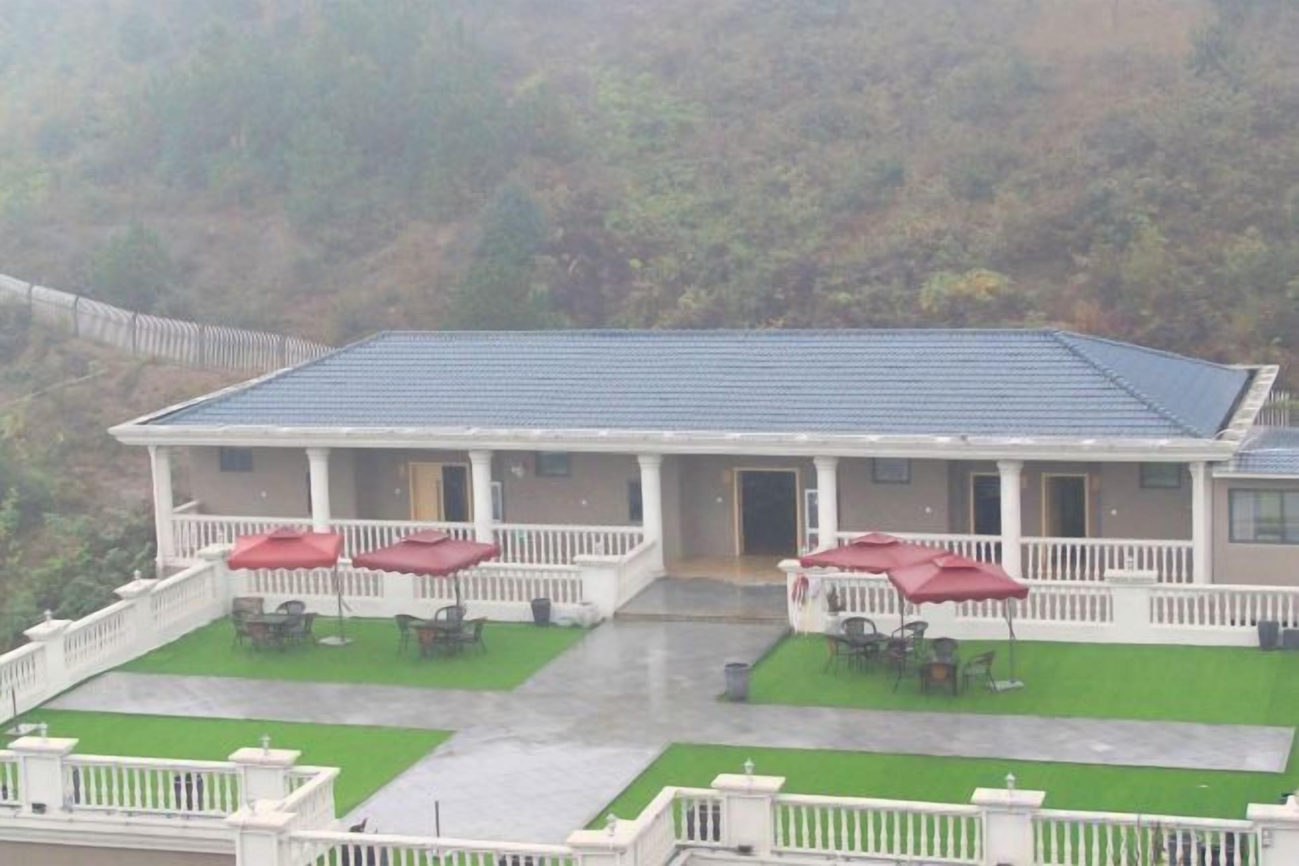 Un edificio con una veranda coperta, posti a sedere all'aperto ombreggiati e un prato verde.