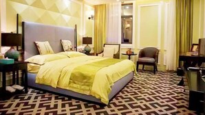 Habitación de hotel con una cama grande, un escritorio, una silla y un televisor.