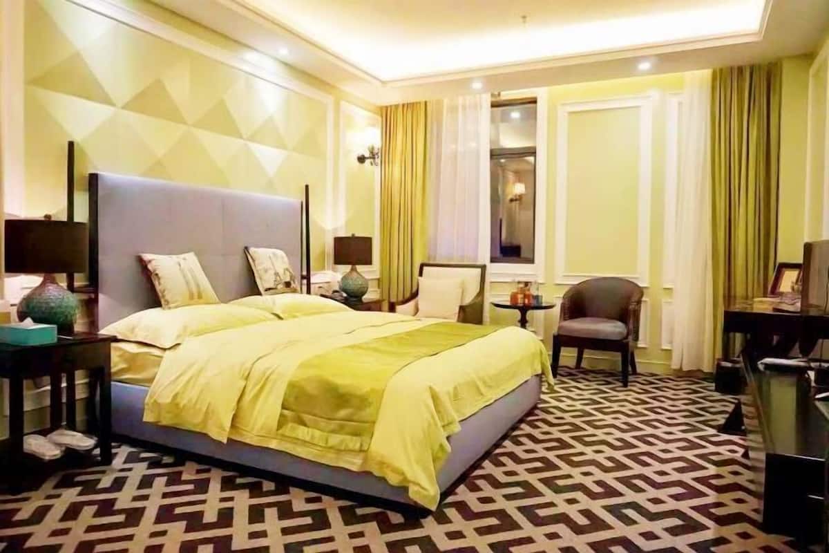 Une chambre d’hôtel avec un grand lit, un bureau, une chaise et un téléviseur.