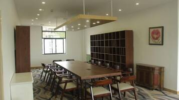 A conference room with a long table, chairs, a bookshelf, and a radiator.
