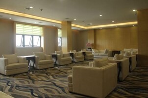 Un hall de hotel con varias zonas de estar, incluyendo sofás y sillones, dispuesto en un espacio amplio.