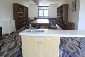 A conference room with a long table, chairs, a white counter with a sink, and built-in shelving.