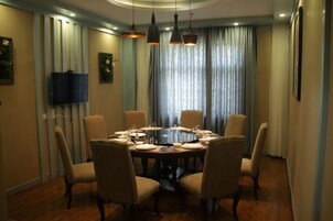 A dining area with a round table, six chairs, and a television on the wall.