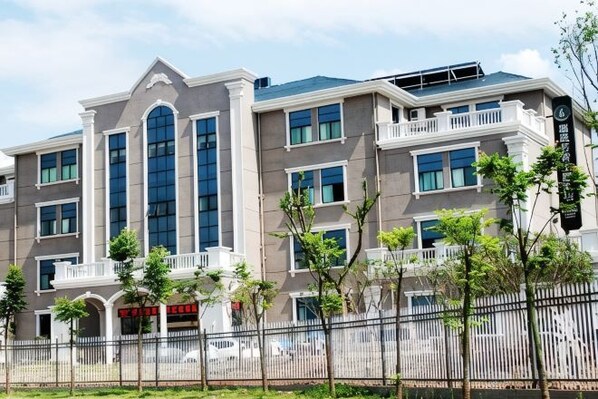 A multi-story building with a symmetrical facade, large windows, and a gated entrance.