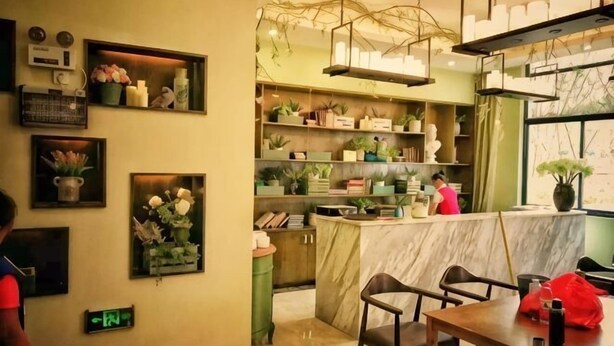 Un restaurante con mostrador de mármol, estantes con plantas y cuadros en las paredes.