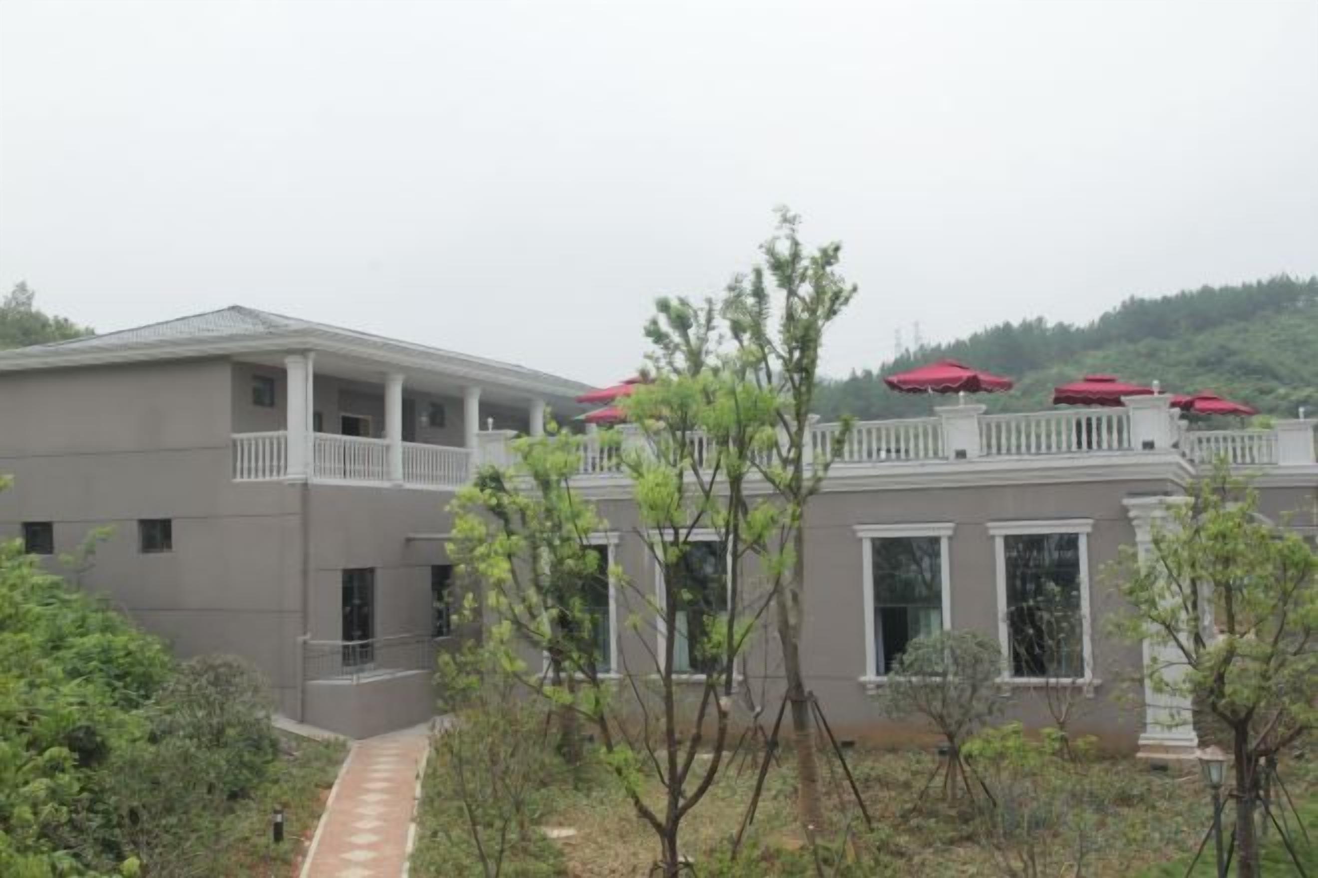 A building with a balcony, a covered walkway, and a view of a hilly landscape.
