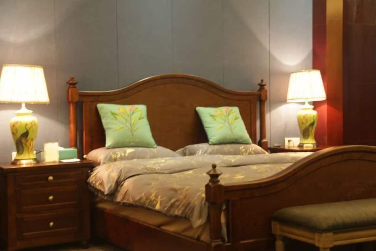Un lit bien fait, avec deux oreillers, une tête de lit en bois et deux lampes de chevet.