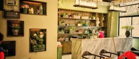 A restaurant interior with a marble counter, shelves with plants, and a bar area.