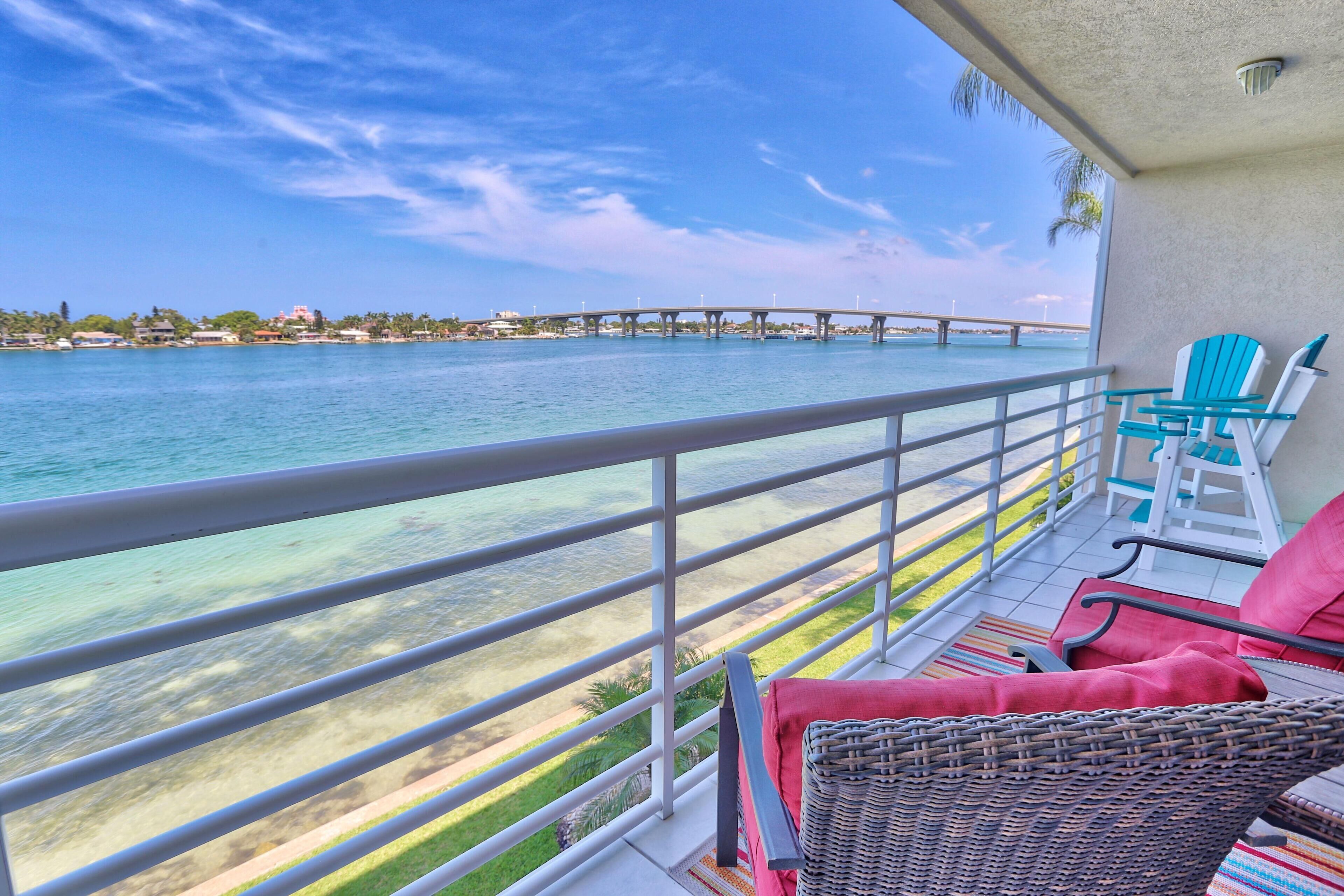 A balcony with a view of the sea, a bridge, and a distant shoreline.