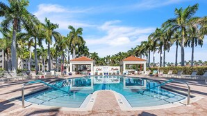 A swimming pool with lounge chairs and palm trees.