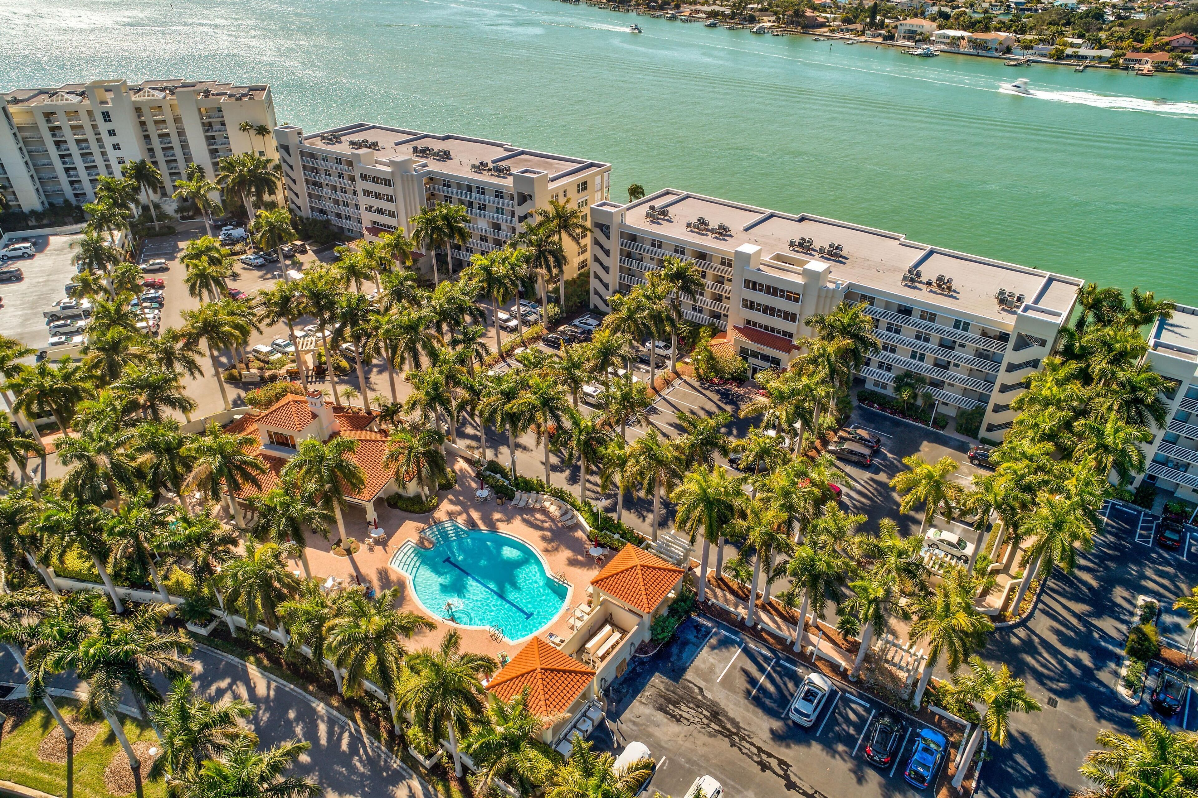 A resort with multiple buildings, a central swimming pool, and palm trees.