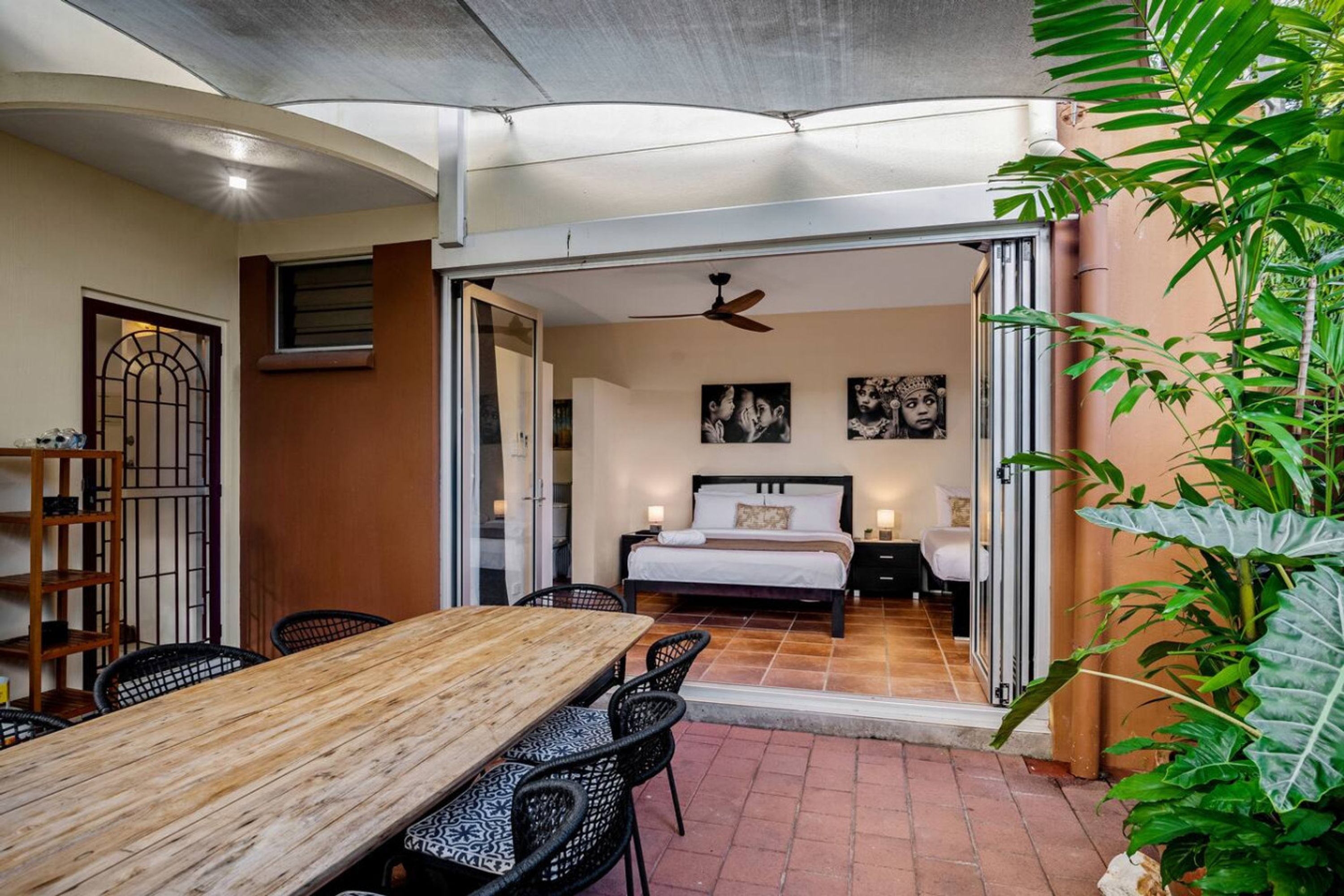 Ein Hotelzimmer mit Bett, Schreibtisch und Stühlen. Es gibt einen Balkon mit Pflanzen.