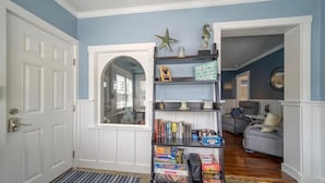 A hallway with a bookshelf, a gray sofa, and a door. - Good Vibrations - Beach House (Treasure Island)