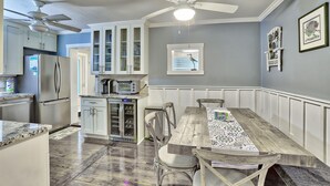 A kitchen with white cabinets, a wooden dining table, and a ceiling fan. - Good Vibrations - Beach House (Treasure Island)