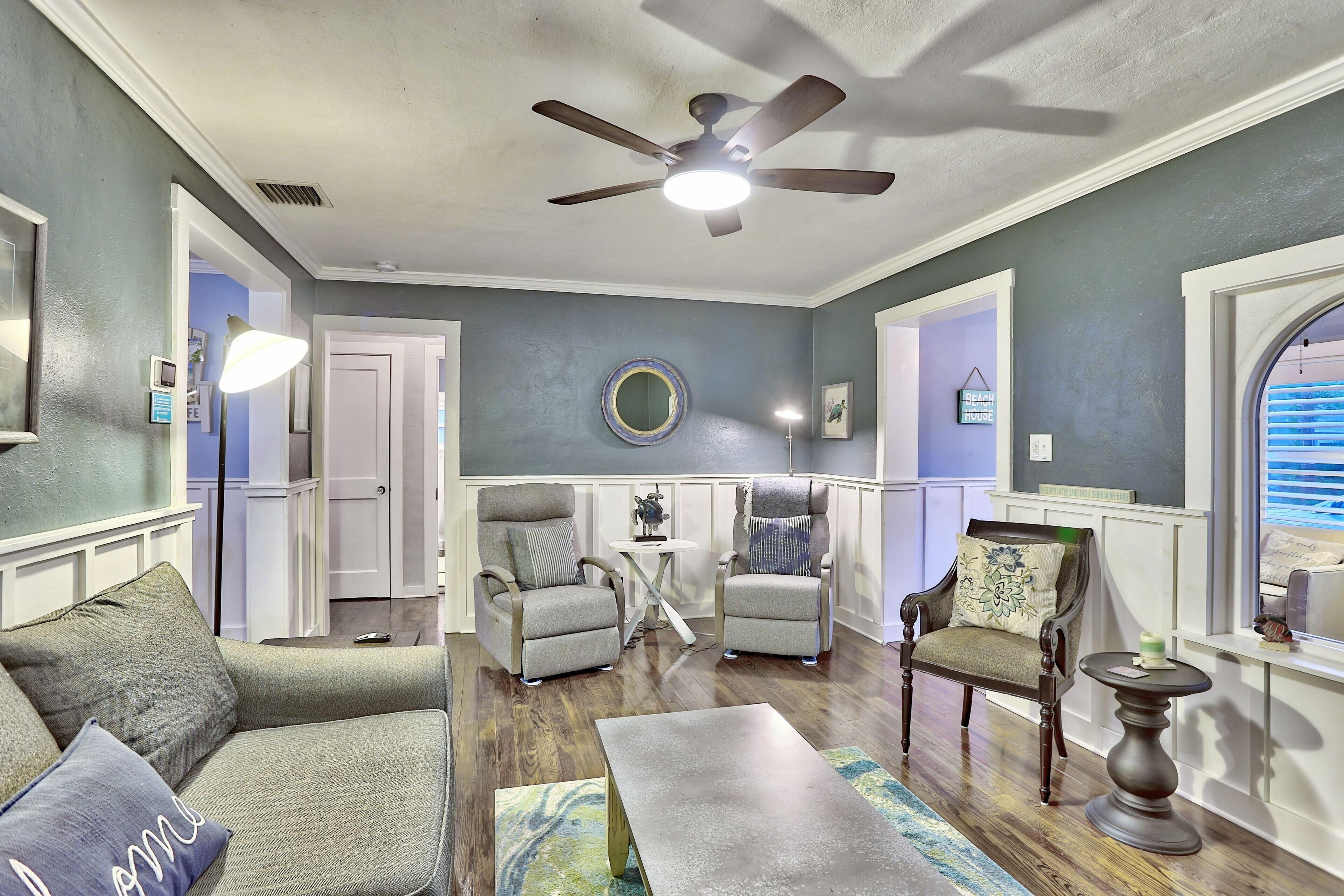 A living room with a ceiling fan, two armchairs, a sofa, a coffee table, and a side table.