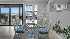 A dining area with white chairs and a table, a balcony with a view, and a decorative tree. - Sugar Dunes 211 (Navarre)