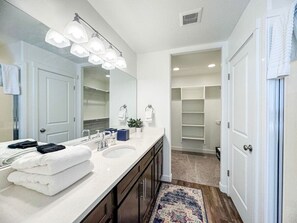 A modern bathroom with a double sink vanity, a large mirror, and a walk-in closet. - Avani Home, Dog friendly, close to Market/Marina (Garden City)
