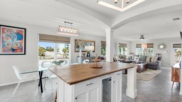 A spacious living area with a kitchen island, dining table, and seating.