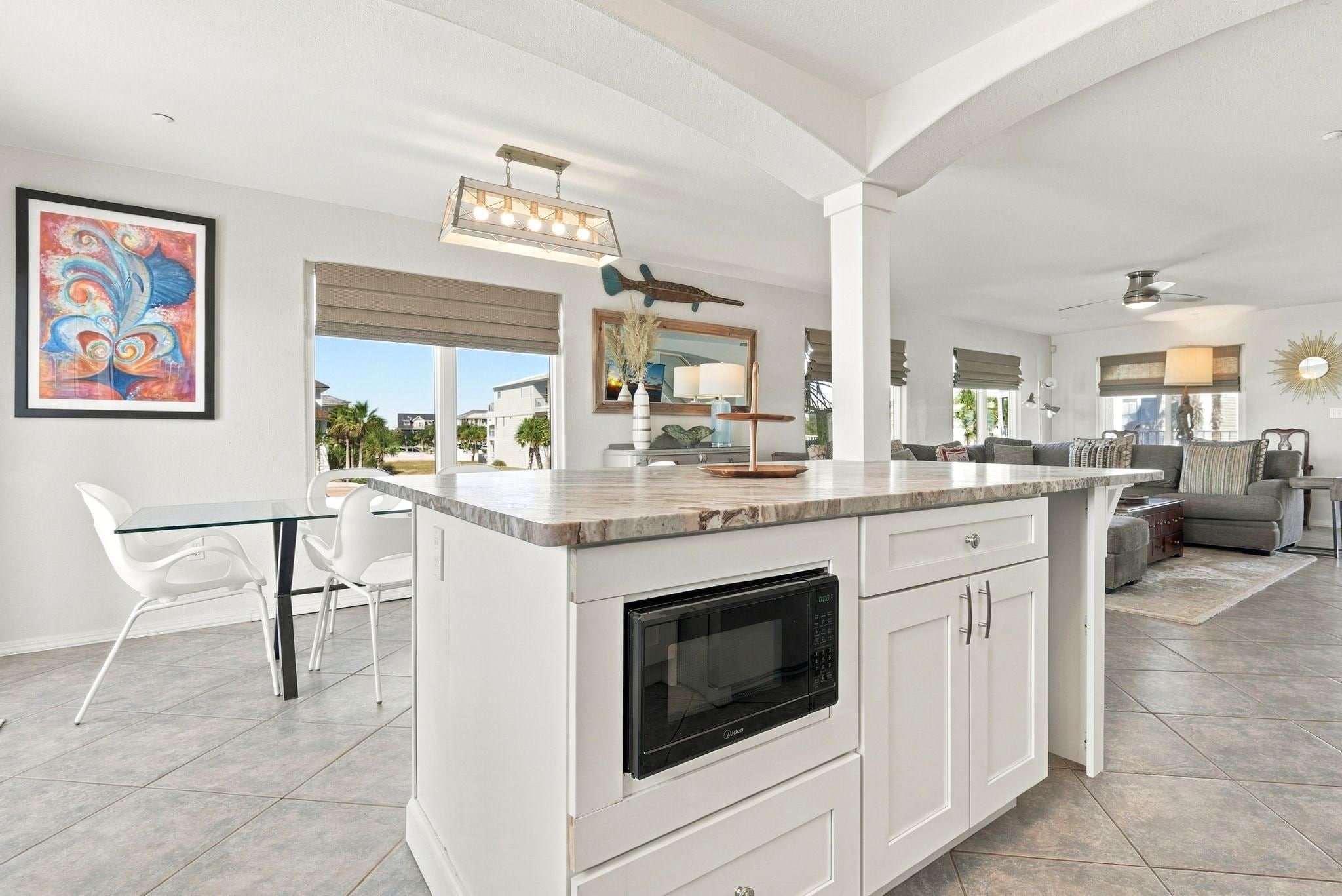 A modern kitchen with a central island, white cabinetry, and a built-in oven.