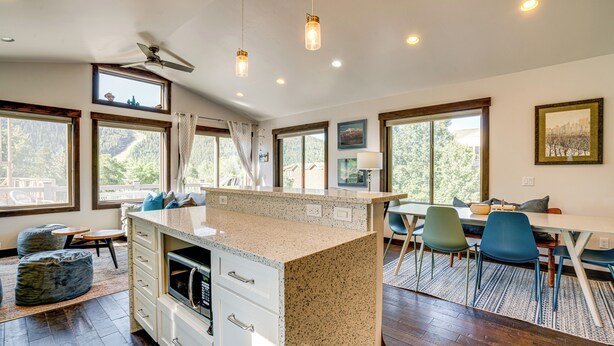 A modern kitchen with a granite countertop, white cabinetry, and a built-in microwave. There are large windows offering views of the outdoors. - Hike, Soak & Play: Keystone Home w/ Views! (Keystone)