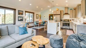 A spacious living area with a sofa, ottoman, and coffee table, a kitchen with wooden cabinets and appliances, and a dining area with chairs and a table. - Hike, Soak & Play: Keystone Home w/ Views! (Keystone)