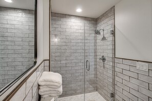 Ein modernes Badezimmer mit einer gläsernen Duschkabine, weißen Fliesenwänden und einem sichtbaren Handtuchhalter.