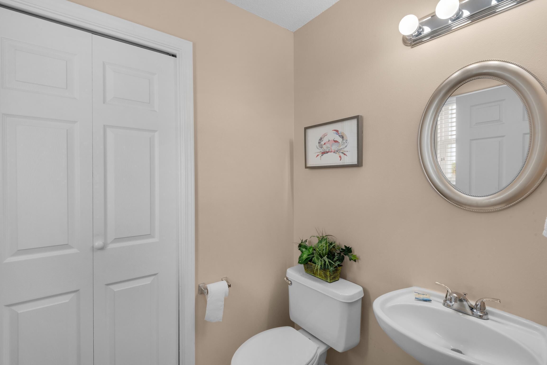 A bathroom with a toilet, sink, and mirror.