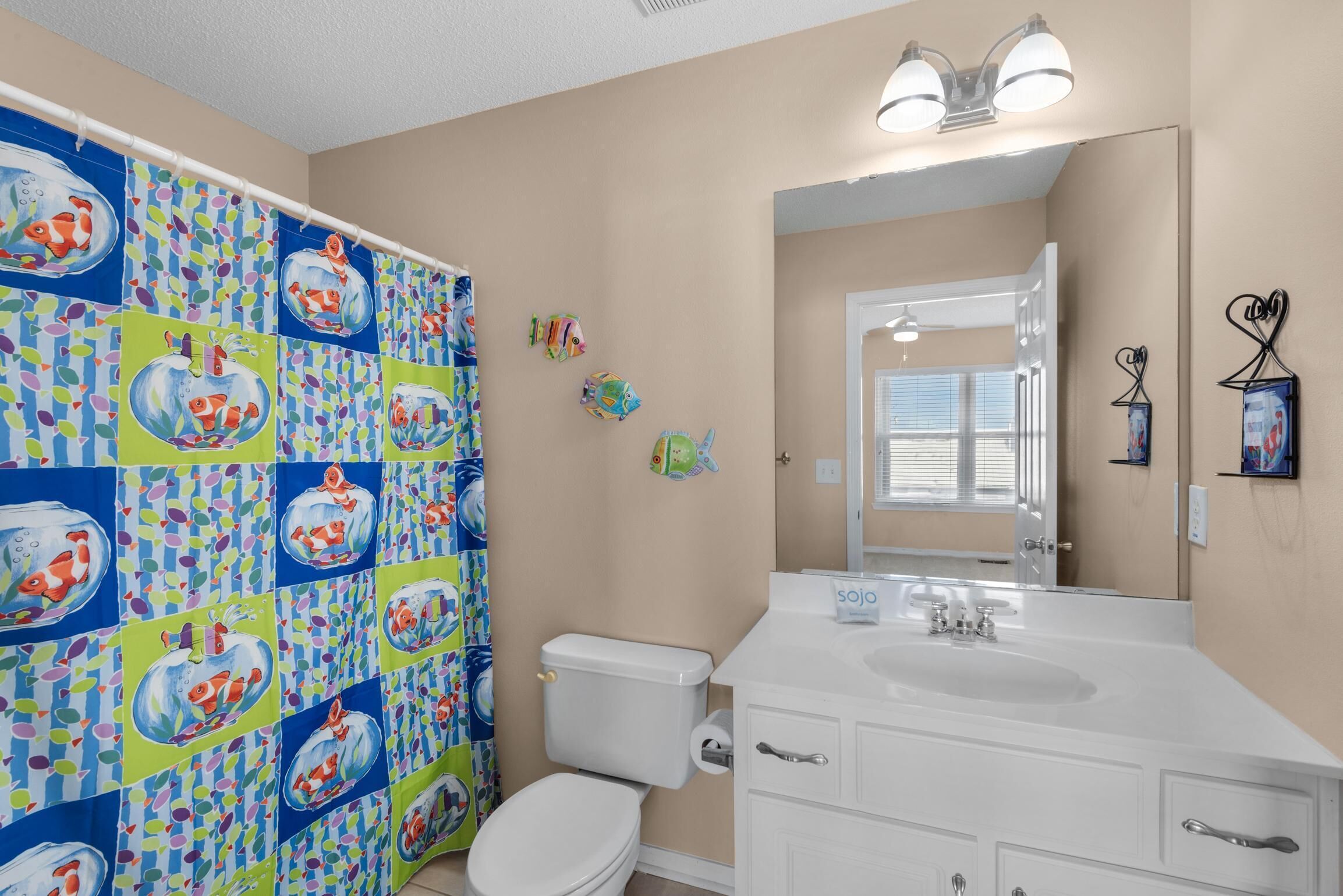 Un baño con lavabo blanco, espejo y retrete.