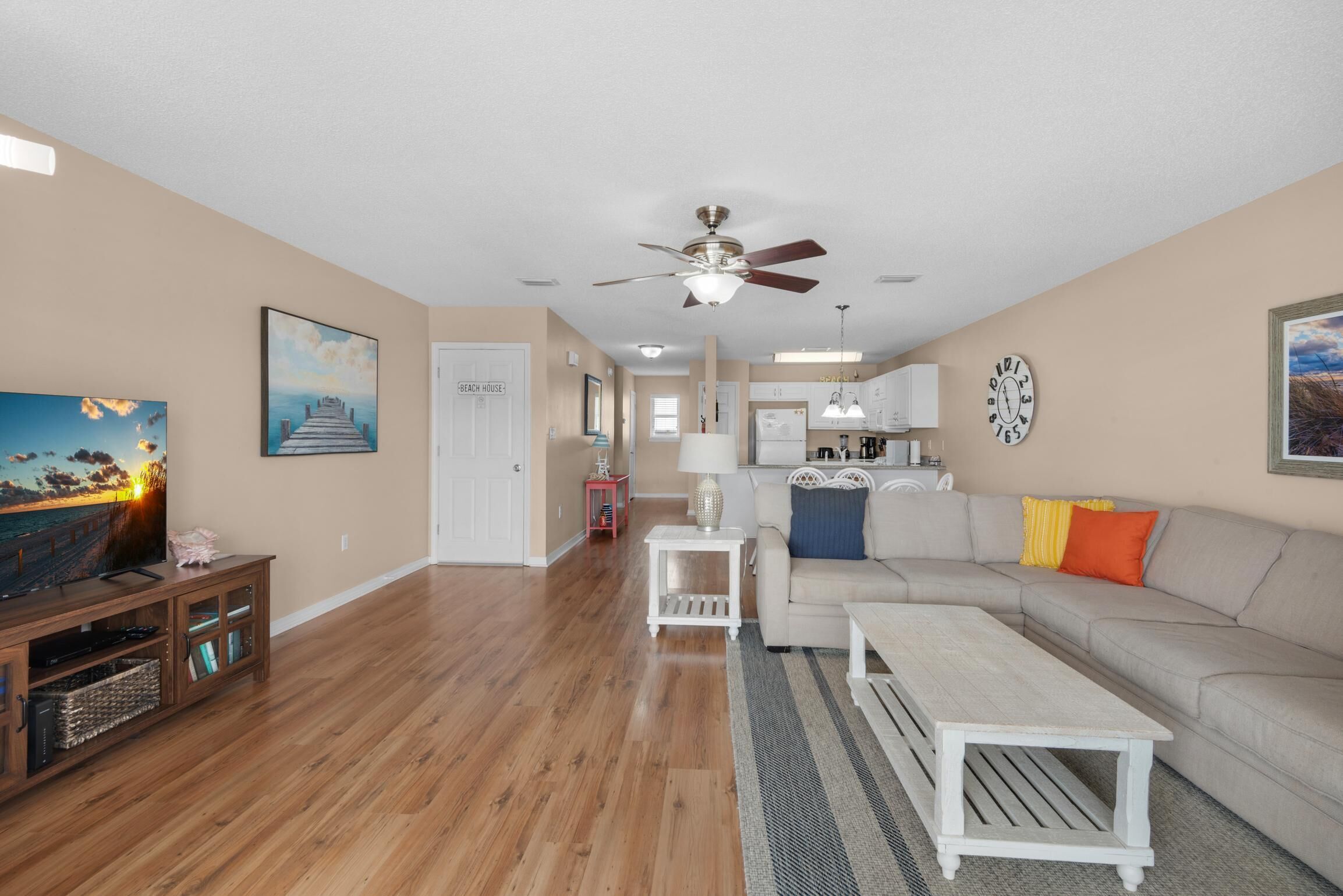 A living room with a television, sofa, coffee table, and a hallway leading to a kitchen.