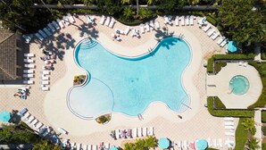 An aerial view of a resort with a large pool, sun loungers, and palm trees. - Studio at the PGA (Port St. Lucie)