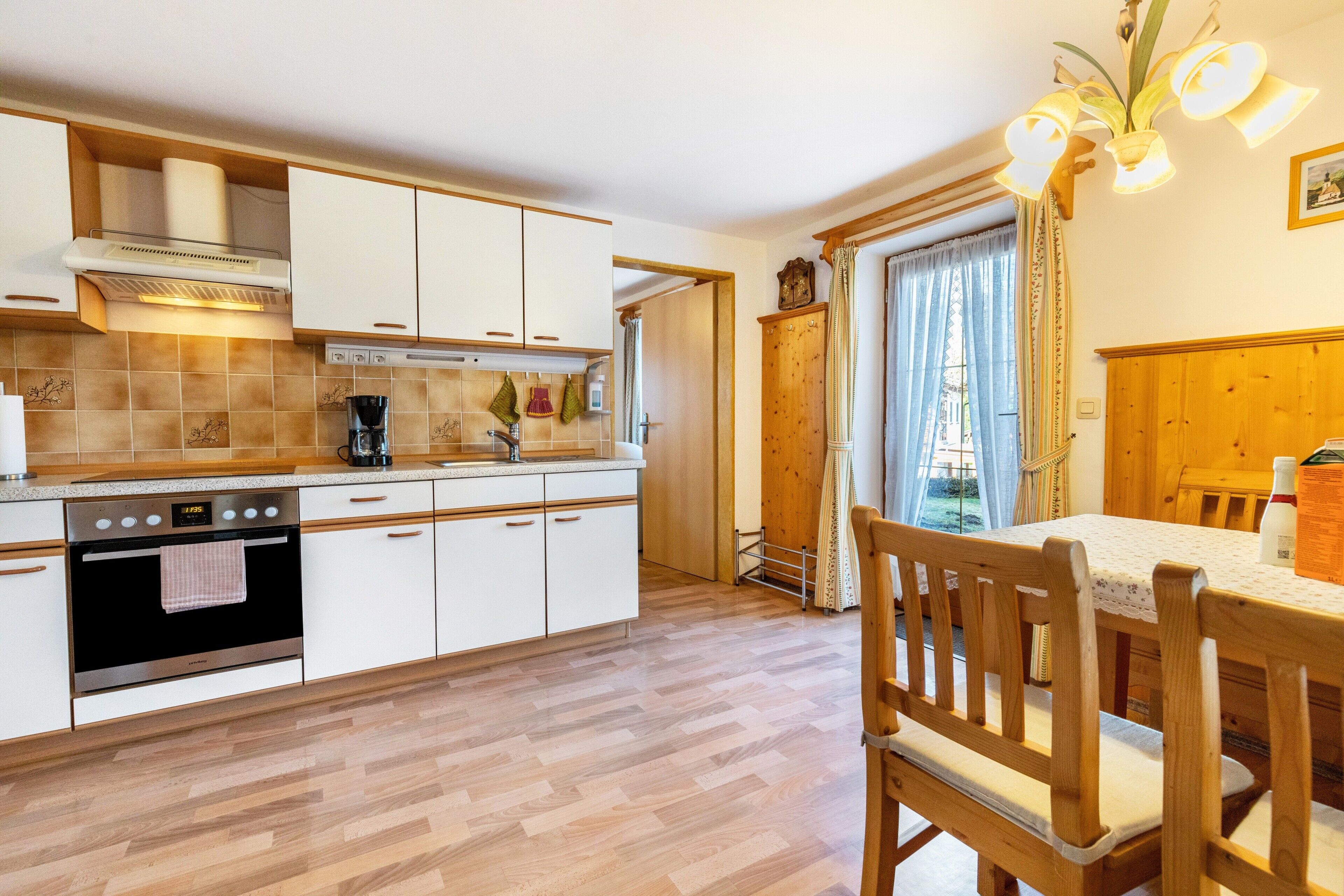 A kitchen with white cabinets, a stove, and a dining area with a table and chairs.