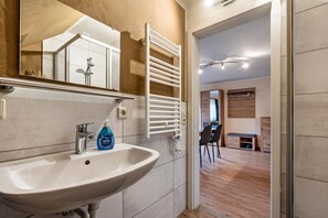 Une salle de bain équipée d’un lavabo, d’un miroir, d’un porte-serviettes et d’une douche.