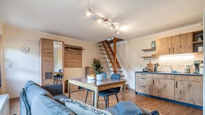 Une cuisine moderne avec des meubles en bois, une table à manger et un escalier.