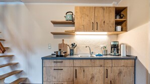 Une cuisine avec des meubles de rangement en bois, un plan de travail, une bouilloire, une machine à café et un évier.