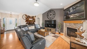 Un salon moderne avec un canapé en cuir, une cheminée, un téléviseur et une grande horloge murale.