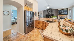 Une cuisine moderne dotée d’appareils électroménagers en acier inoxydable, de meubles en bois et d’une grande horloge murale.