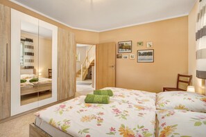 Une chambre à coucher avec un lit, un miroir, un escalier et des tableaux accrochés au mur.