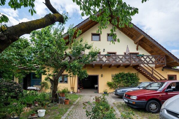 A two-story house with a balcony, a driveway, and parked cars.