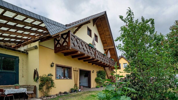 A traditional chalet with a sloped roof, wooden balcony, and a small garden area. - Holiday Home 'Bauernnest' with Shared Garden and Wi-Fi (Schmogrow-Fehrow)