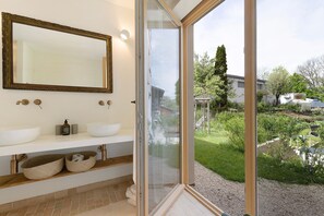 Un bagno con un ampio specchio, due lavabi e una finestra vista giardino.